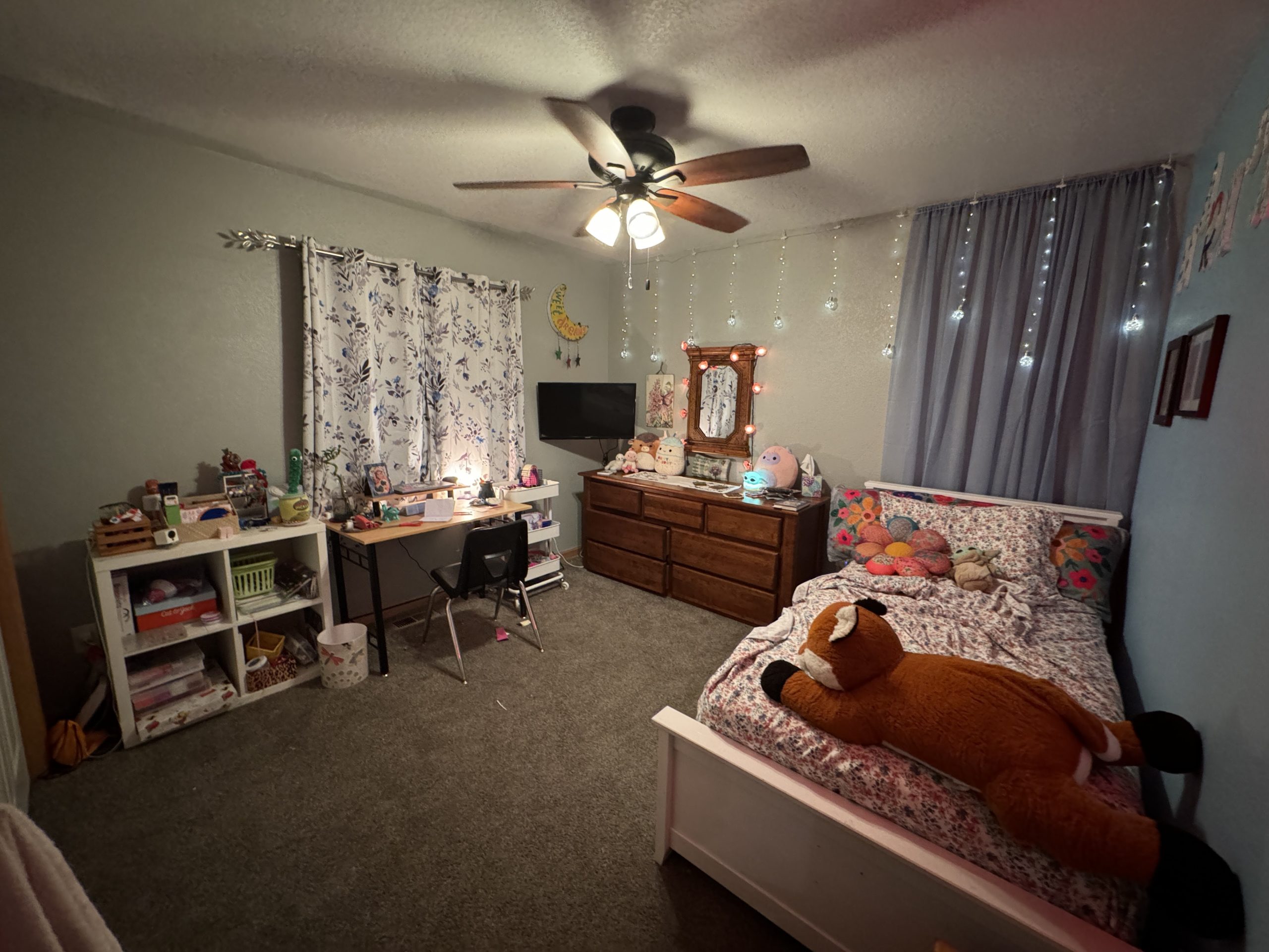 Mariana's finished bedroom, with grey walls, with a sky-blue wall on the right, her bed, brown dresser, desk, and shelving.